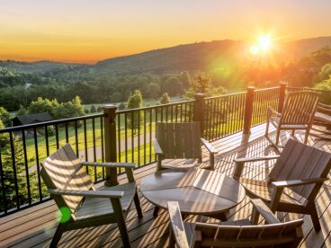 Deck railing on a beautiful deck overlooking green backyard with sun coming up