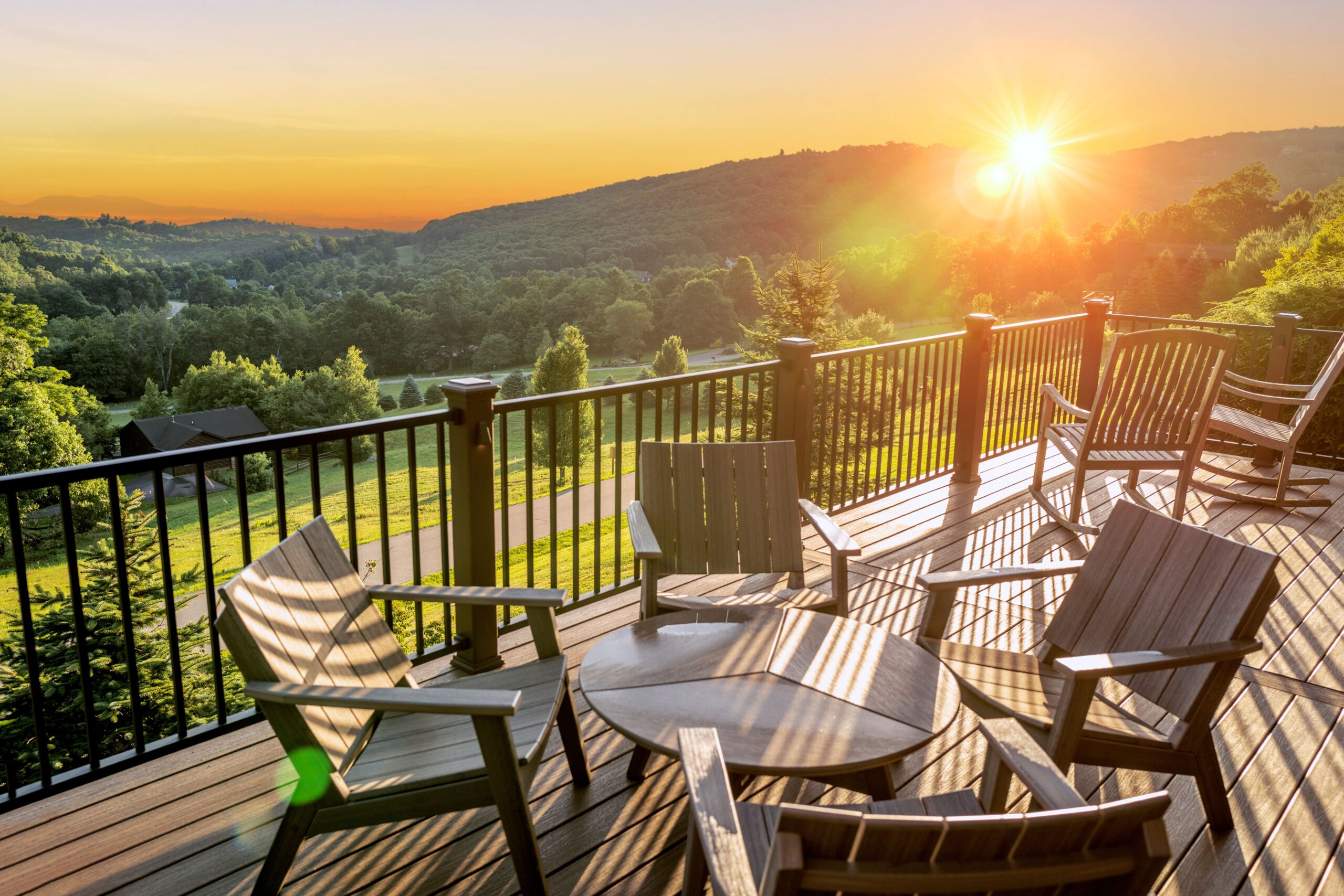 Deck railing on a beautiful deck overlooking green backyard with sun coming up